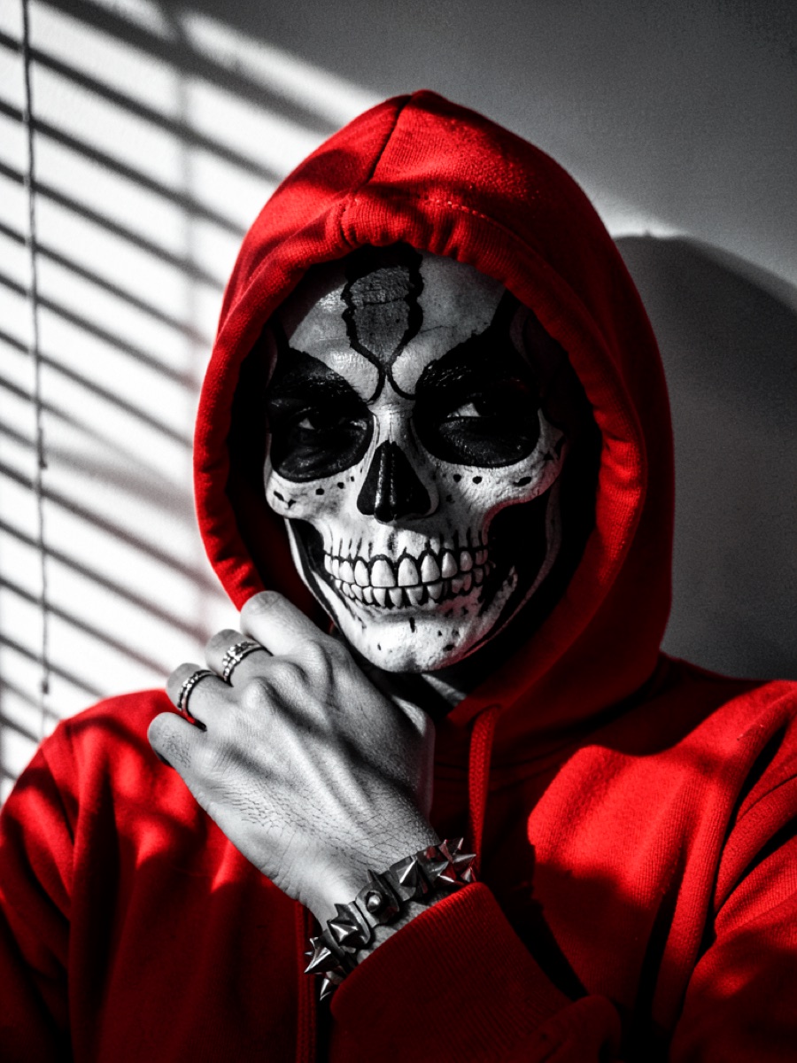 Halloween AI photo prompt example — skull face paint with red hoodie in selective-color noir